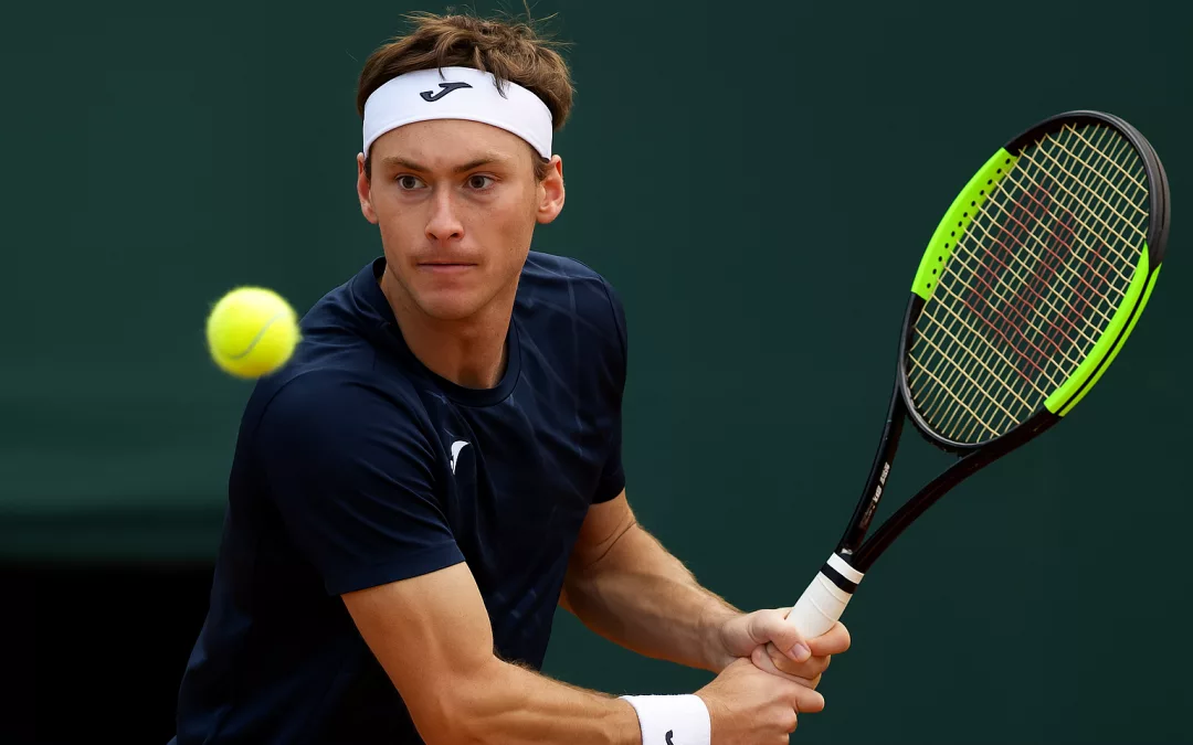 Joueur de tennis gaucher vu de profil en plein échange sur un court extérieur, concentré sur la balle, ambiance sportive et lumineuse.