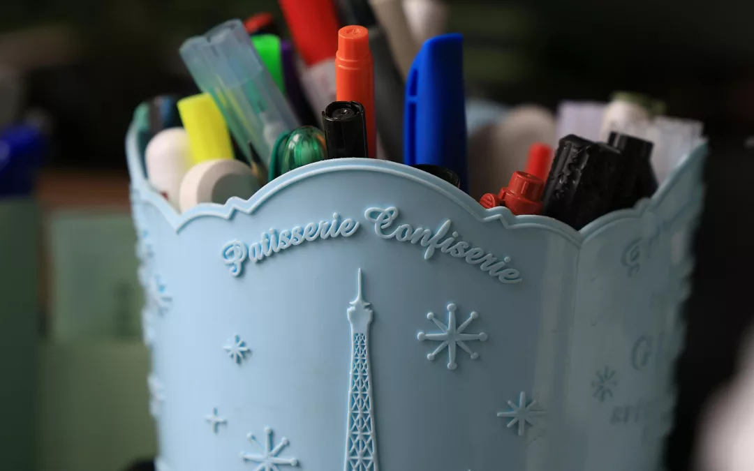 Pot à crayons bleu décoré de la tour Eiffel, rempli de stylos colorés sur un bureau parisien