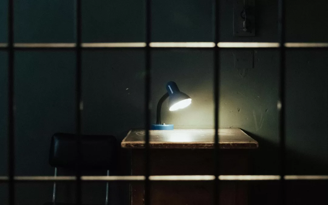 Bureau d’interrogatoire faiblement éclairé par une lampe, symbolisant la justice et la mise en lumière de la vérité.